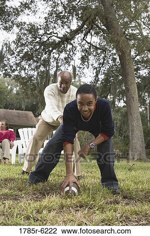 Stock Image - Father and son playing football in backyard. Fotosearch
