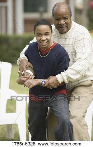 Stock Photograph - Father and son playing football in backyard. Fotosearch