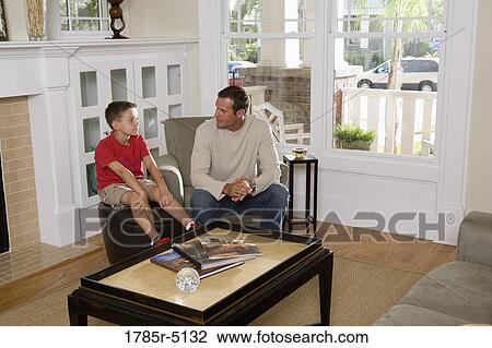 Father and son sitting in a living room View Large Photo Image Stock Image - Father and son sitting in a living room. Fotosearch