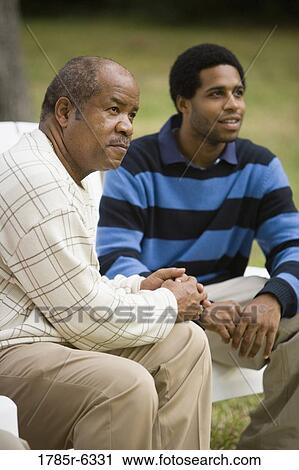 Stock Image - Father and son sitting together. Fotosearch
