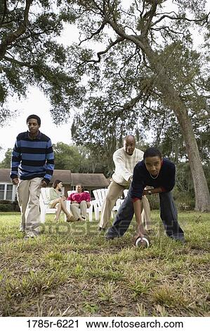 Father and sons playing football in backyard View Large Photo Image Stock Image - Father and sons playing football in backyard. Fotosearch