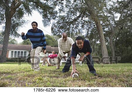 Father and sons playing football in backyard View Large Photo Image Stock Photograph - Father and sons playing football in backyard. Fotosearch