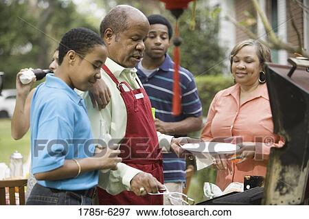 Father grilling hotdogs with family gathered around View Large Photo Image Stock Photo - Father grilling hotdogs with family gathered around. Fotosearch
