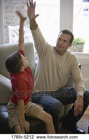 Father high-fiving his son in living room View Large Photo Image Stock Image - Father high-fiving his son in living room. Fotosearch