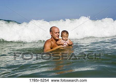 Father playing with baby girl in the ocean waves View Large Photo Image Picture - Father playing with baby girl in the ocean waves. Fotosearch