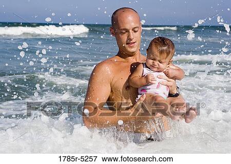 Father playing with baby girl in the ocean waves View Large Photo Image Stock Photo - Father playing with baby girl in the ocean waves. Fotosearch