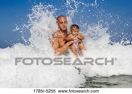 Father playing with baby girl in the ocean waves View Large Photo Image Stock Photography - Father playing with baby girl in the ocean waves. Fotosearch