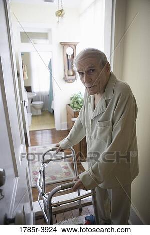 Feeble senior man slowly going down hallway with walker View Large Photo Image Picture - Feeble senior man slowly going down hallway with walker. Fotosearch