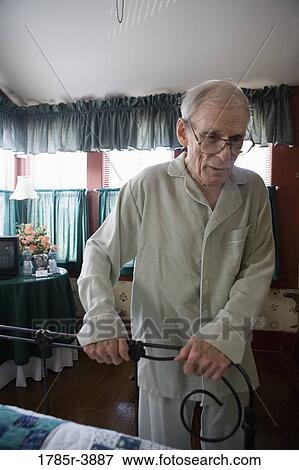 Feeble senior man trying to walk while holding on to bedframe View Large Photo Image Stock Photo - Feeble senior man trying to walk while holding on to bedframe. Fotosearch