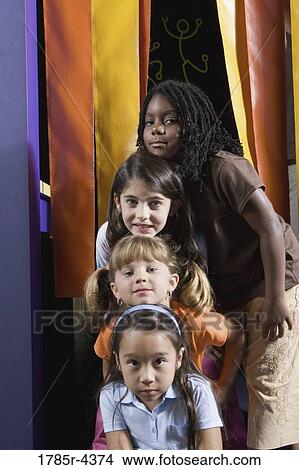 Picture - Four girls placing their heads in a vertical row. Fotosearch