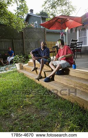 Friends relaxing in backyard on 4th of July View Large Photo Image Stock Image - Friends relaxing in backyard on 4th of July. Fotosearch