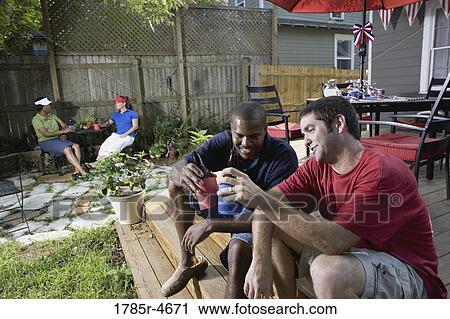 Friends relaxing in backyard on 4th of July View Large Photo Image Stock Image - Friends relaxing in backyard on 4th of July. Fotosearch