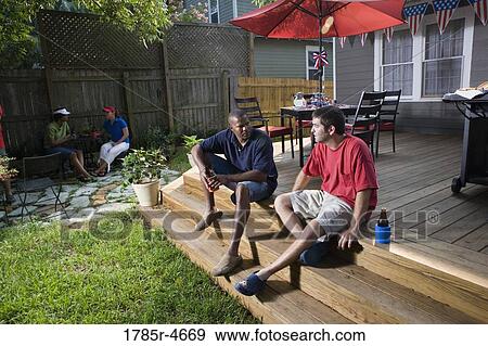 Stock Photo - Friends relaxing in backyard on 4th of July. Fotosearch