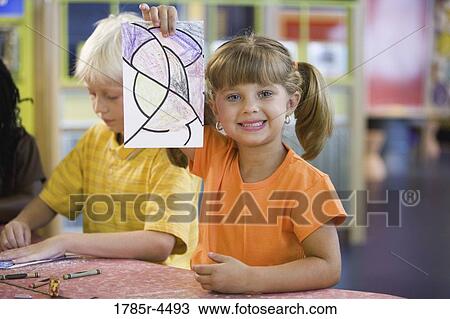 Girl (5-6) showing off her drawing with toothy smile View Large Photo Image Stock Image - Girl (5-6) showing off her drawing with toothy smile. Fotosearch