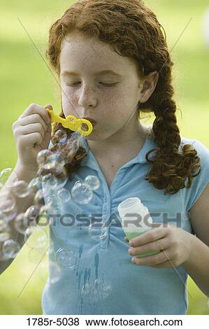 Stock Photo - Girl blowing bubbles at a park. Fotosearch