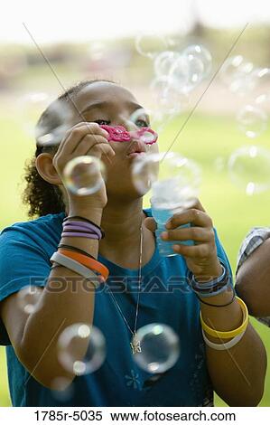 Girl blowing bubbles at a park View Large Photo Image Stock Photography - Girl blowing bubbles at a park. Fotosearch