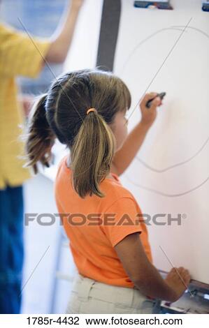 Girl drawing on easel in art class View Large Photo Image Stock Image - Girl drawing on easel in art class. Fotosearch