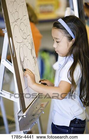 Girl drawing on easel in art class View Large Photo Image Stock Image - Girl drawing on easel in art class. Fotosearch