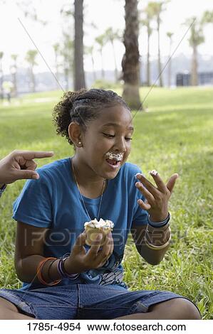 Girl eating a cupcake at a park View Large Photo Image Picture - Girl eating a cupcake at a park. Fotosearch