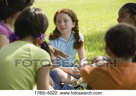 Stock Image - Girl in group listening to teacher. Fotosearch