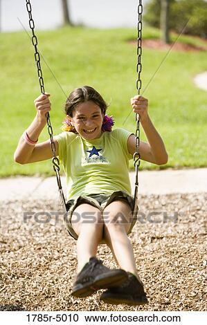 Girl laughing while playing on swing at a playground View Large Photo Image Stock Image - Girl laughing while playing on swing at a playground. Fotosearch