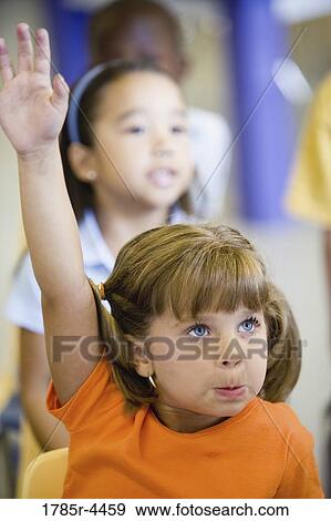 Girl raising hand in a classroom View Large Photo Image Stock Photo - Girl raising hand in a classroom. Fotosearch