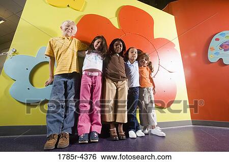 Stock Photograph - Girls and boy standing against a colorful wall. Fotosearch