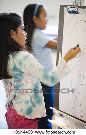 Girls drawing on easel in art class View Large Photo Image Stock Image - Girls drawing on easel in art class. Fotosearch