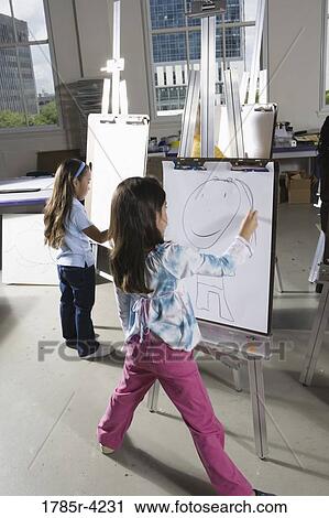 Girls drawing on easels in art class View Large Photo Image Stock Image - Girls drawing on easels in art class. Fotosearch
