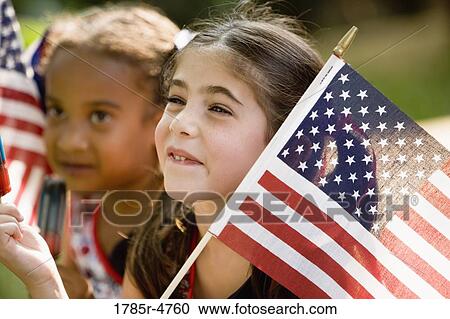 Stock Image - Girls eating popsicles waving US flags. Fotosearch