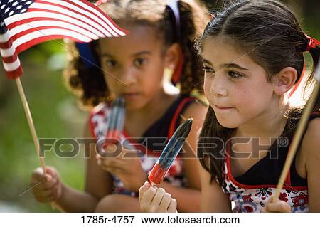 Girls eating popsicles waving US flags View Large Photo Image Stock Photo - Girls eating popsicles waving US flags. Fotosearch