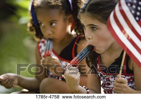Girls eating popsicles waving US flags View Large Photo Image Stock Photo - Girls eating popsicles waving US flags. Fotosearch