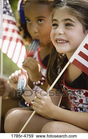 Girls eating popsicles waving US flags View Large Photo Image Stock Photo - Girls eating popsicles waving US flags. Fotosearch