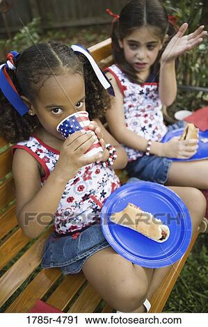 Girls sitting on bench with eating hotdogs View Large Photo Image Stock Image - Girls sitting on bench with eating hotdogs. Fotosearch