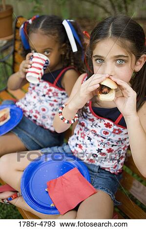 Girls sitting on bench with eating hotdogs View Large Photo Image Stock Image - Girls sitting on bench with eating hotdogs. Fotosearch