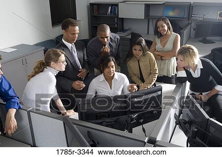 Picture - Group of young workers in office gathered around computer screen. Fotosearch