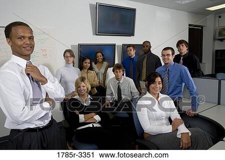 Stock Image - Group of young workers in office gathered for a meeting. Fotosearch