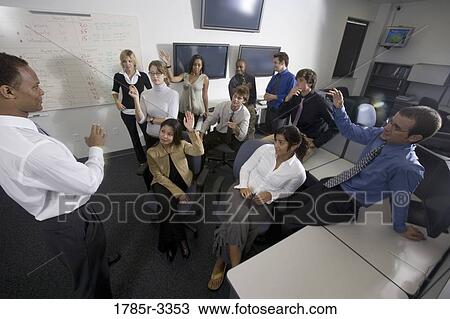 Stock Image - Group of young workers in office gathered for a meeting. Fotosearch