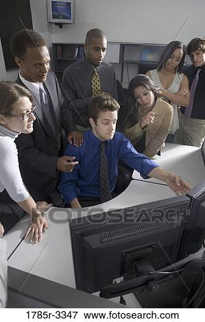 Stock Photo - Group of young workers in office gathered around computer screen. Fotosearch