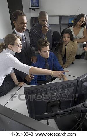 Stock Photo - Group of young workers in office gathered around computer screen. Fotosearch