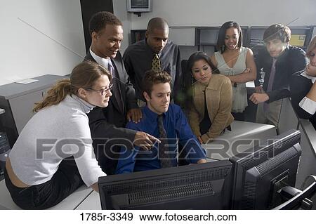 Stock Photo - Group of young workers in office gathered around computer screen. Fotosearch