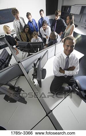 Stock Photograph - Group of young workers in office gathered around computer screen. Fotosearch
