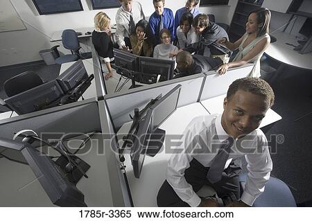 Stock Photography - Group of young workers in office gathered around computer screen. Fotosearch