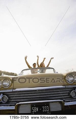 Happy, cheerful and waving young couple sitting in antique convertible car View Large Photo Image Stock Photography - Happy, cheerful and waving young couple sitting in antique convertible car. Fotosearch