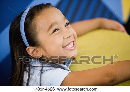 Stock Photograph - Head-shot of a young girl in a colorful room. Fotosearch