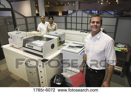 Stock Image - High angle view of a office colleagues by office equpment. Fotosearch