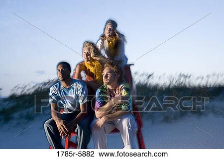 Stock Image - Hippies hanging out at the beach on lifeguard chair. Fotosearch
