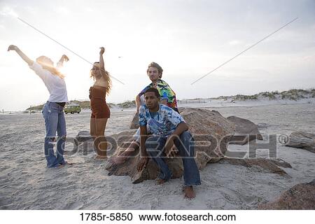 Stock Image - Hippies hanging out at the beach. Fotosearch