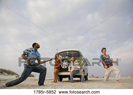 Stock Image - Hippies hanging out at the beach. Fotosearch