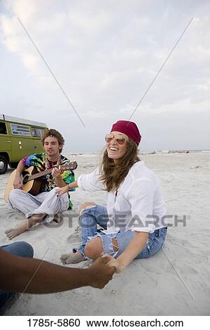 Stock Image - Hippies hanging out at the beach. Fotosearch